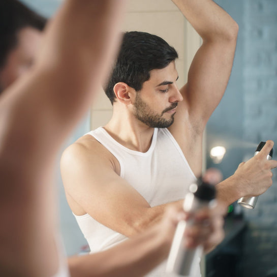 Un homme utilisant un déodorant en spray avec gaz propulseur, nocif pour l'environnement